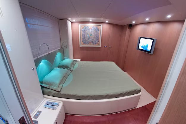 Modern bedroom with a large electric bed, wall-mounted TV, and ambient lighting.