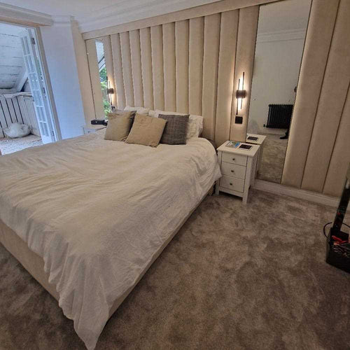 A bedroom with an Ottoman king-size bed, cream tufted headboard, bedside tables, and a large mirror.