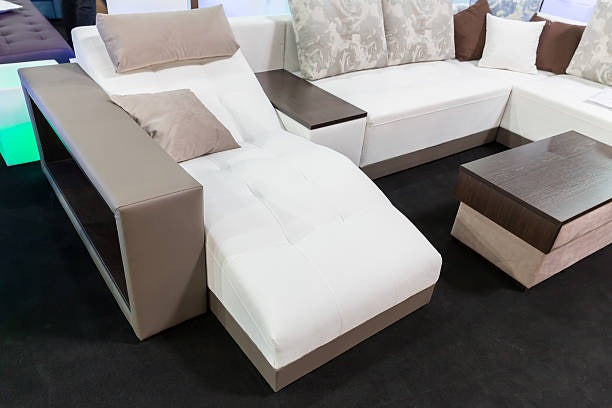 Modern L-shaped leather sofa bed with white and light brown upholstery and a chaise lounge.