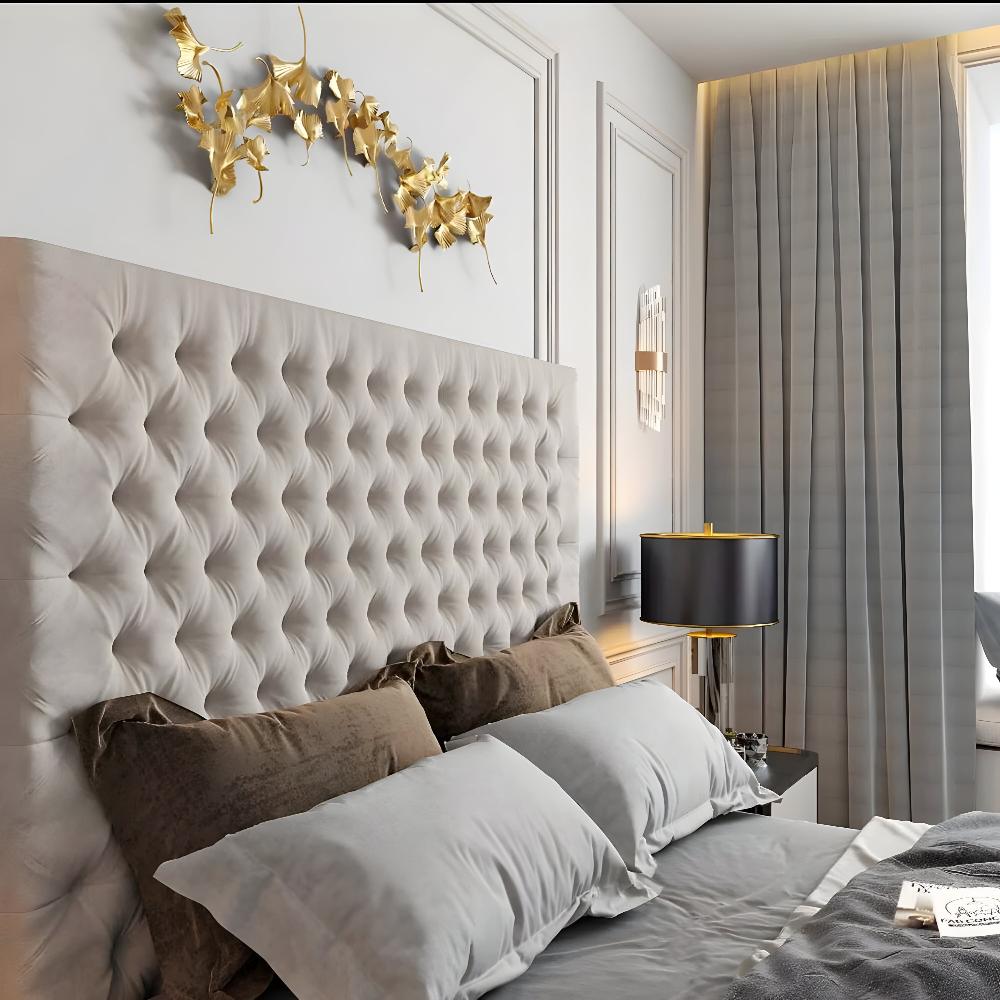 A bedroom with a tufted beige headboard Mini Chester Tv Bed Frame, decorative golden leaf wall art, and a black and gold table lamp.