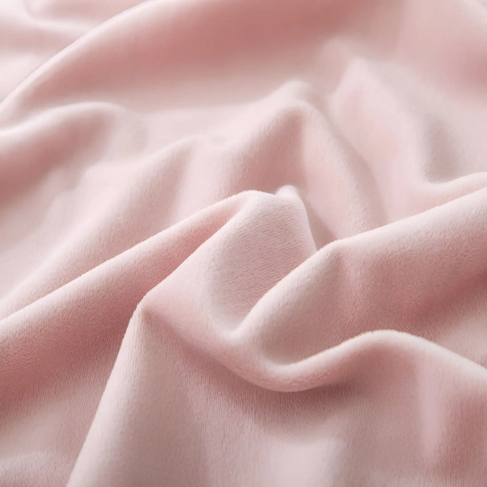 Close-up of a pink, soft fabric with a smooth, velvety texture, shown in gentle waves and folds, illuminated to highlight its plushness.