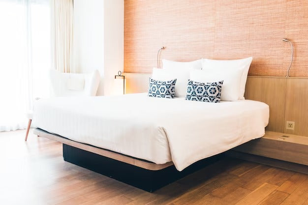 Modern bedroom with a Murphy bed , blue patterned pillows, and wooden accents.